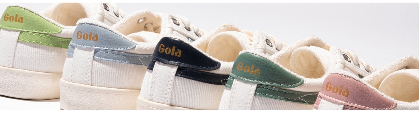 Close-up of five Gola sneakers in white with colorful heel tabs: green, blue, navy, dark green, and pink.