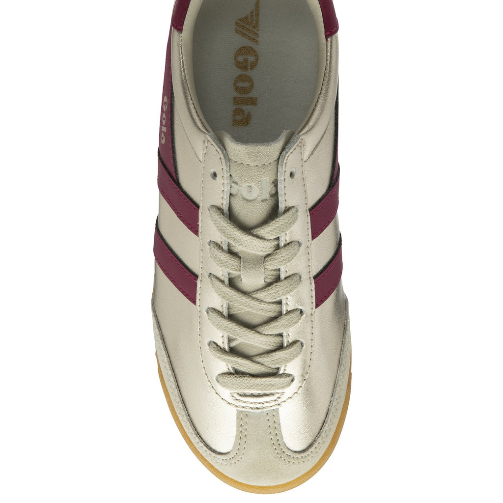The top view of a golden Gola sneaker with burgundy stripes.